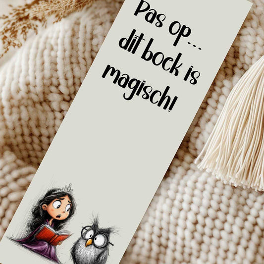 Close-up van een boekenlegger met de tekst 'Pas op... dit boek is magisch!' en een prinses die een rood boek leest naast een uil. Naast de boekenlegger ligt een crèmekleurig kwastje.