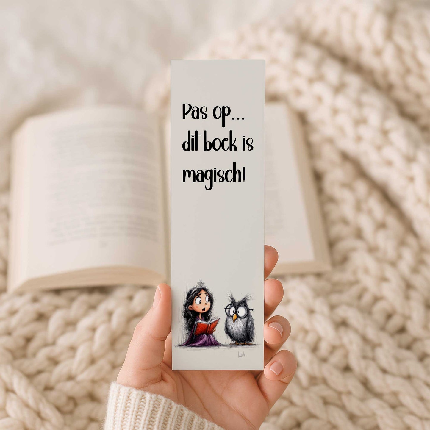 Hand houdt een boekenlegger vast met de tekst 'Pas op... dit boek is magisch!' en een illustratie van een prinses met een rood boek naast een uil. Op de achtergrond ligt een open boek.