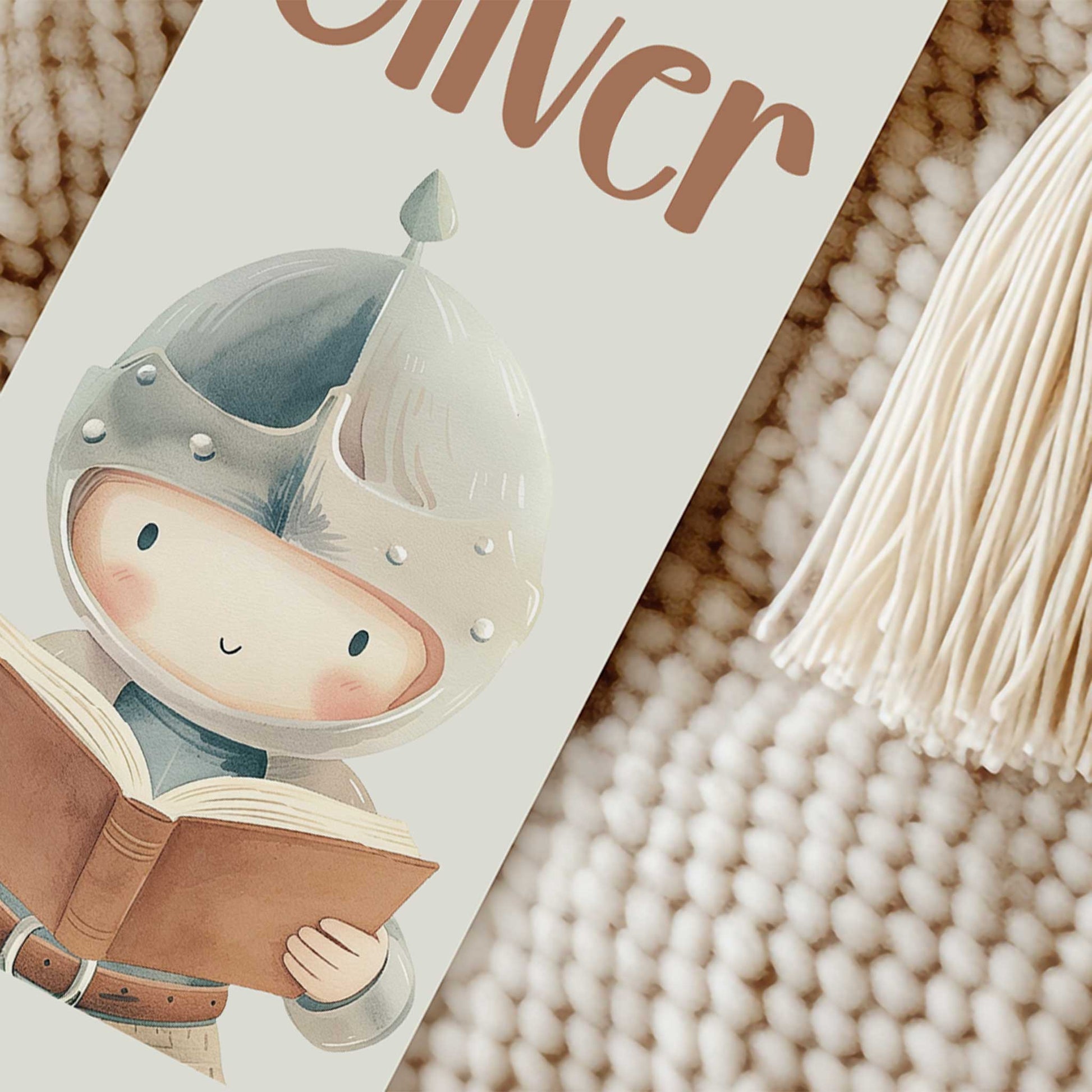 Close-up van een gepersonaliseerde boekenlegger met de naam Oliver, een lezende ridder en een wit kwastje.