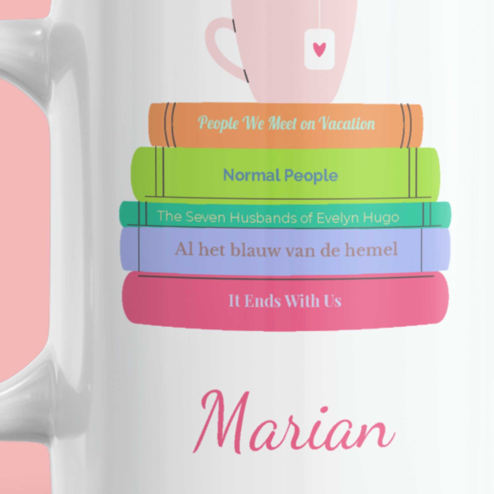 Detailfoto van witte mok met boekenstapel design en naam Marian, vrolijke kleuren en theekopje