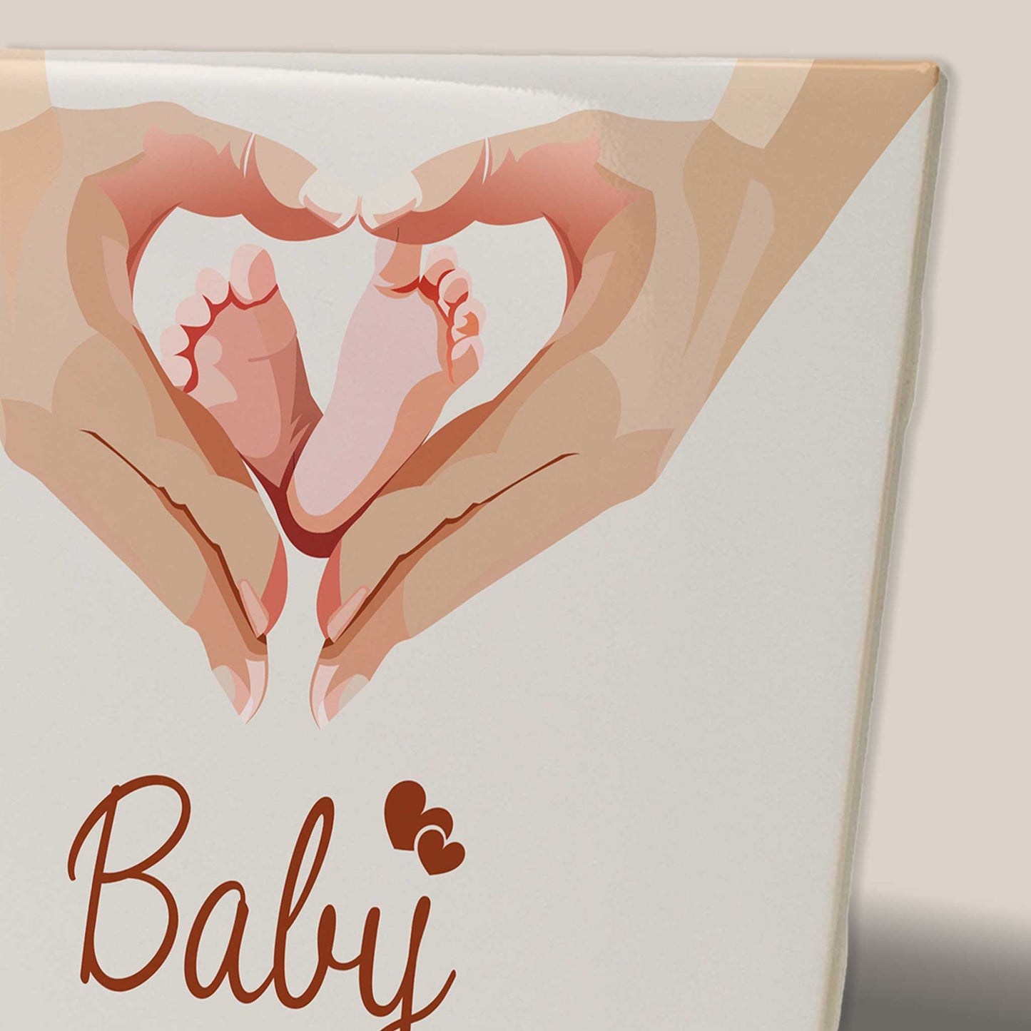 Close-up van keramisch babytegeltje met illustratie van babyvoetjes in een hart gevormd door handen en de tekst Baby