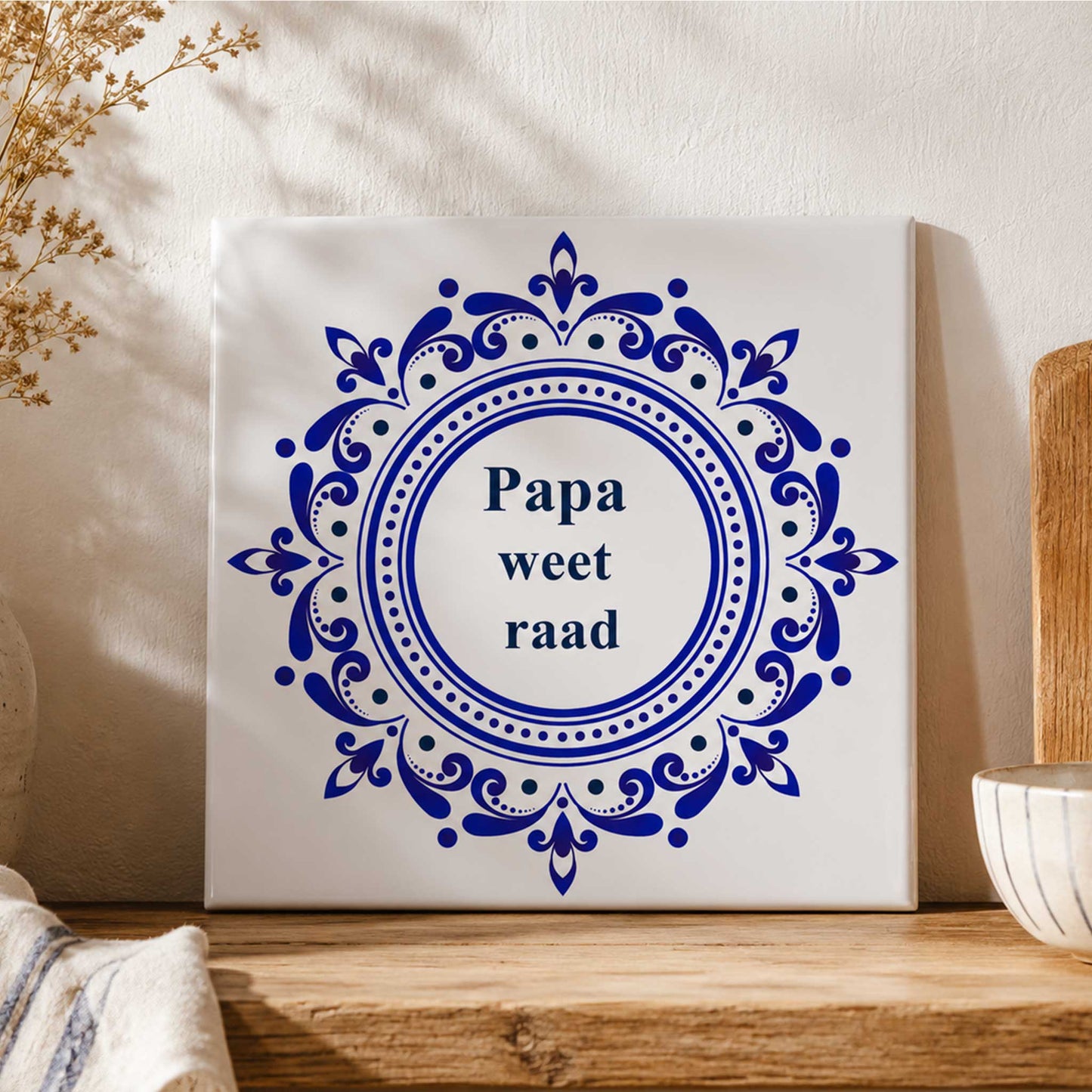 Delfts blauw keramisch tegeltje met de tekst “Papa weet raad” op houten plank in warme landelijke keukenstijl