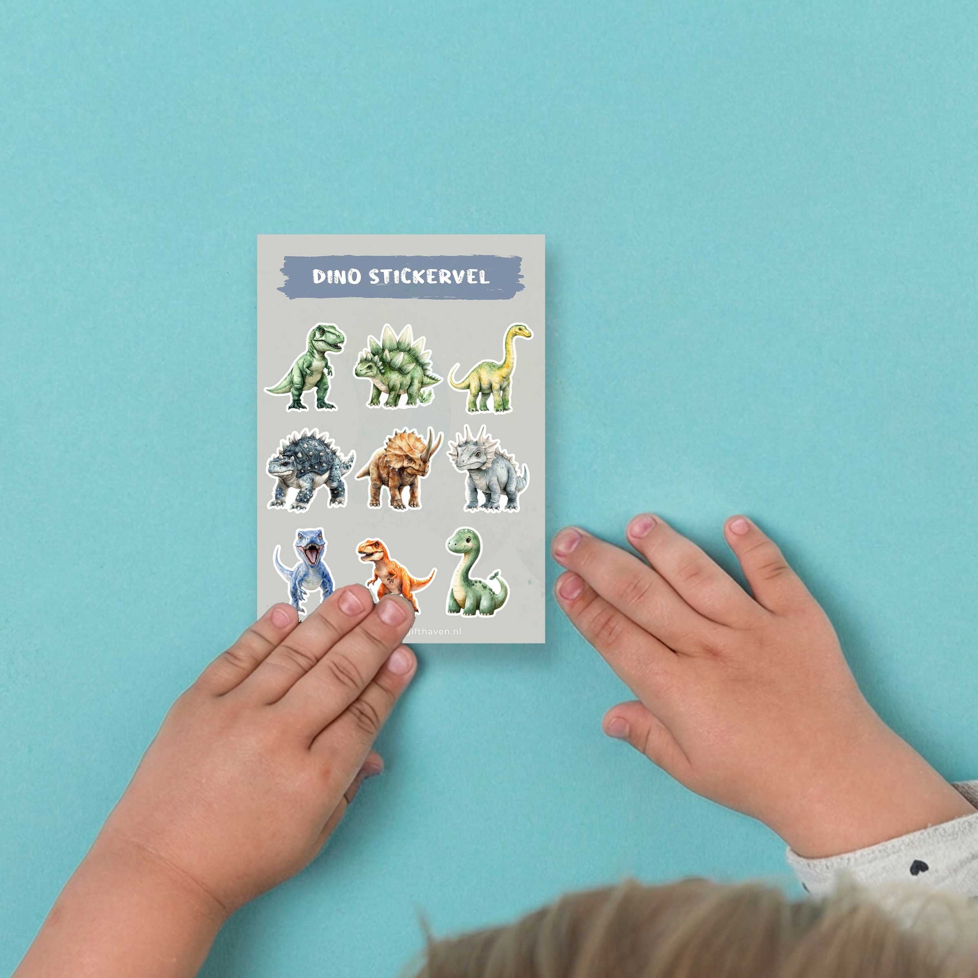 Kinderhanden die een dino stickervel vasthouden op een blauwe achtergrond.