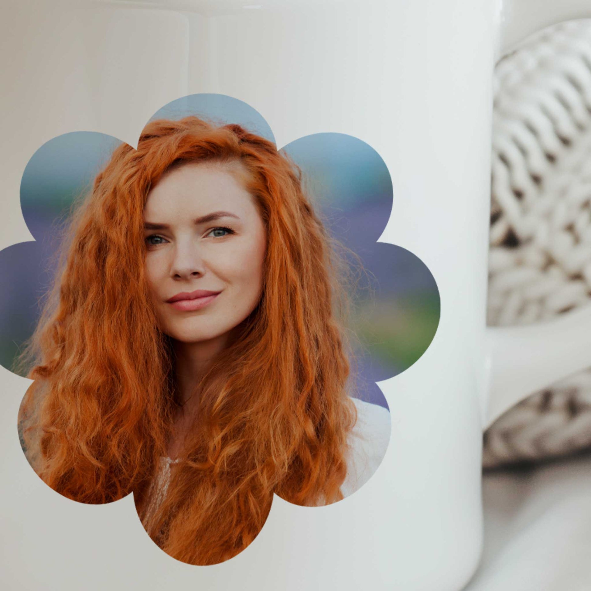 Close-up van een gepersonaliseerde witte fotomok met een portretfoto van een roodharige vrouw in een bloemvormig kader op de voorkant van de mok.
