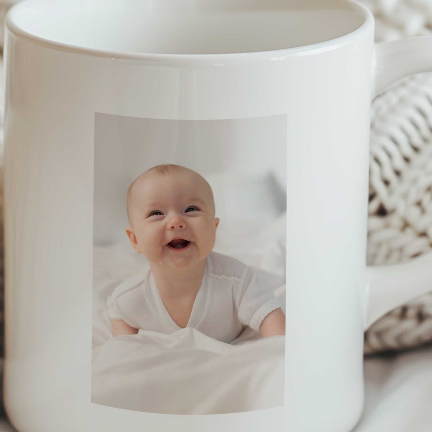 Close-up van een witte keramische mok met rechthoekige foto van een lachende baby aan de voorzijde