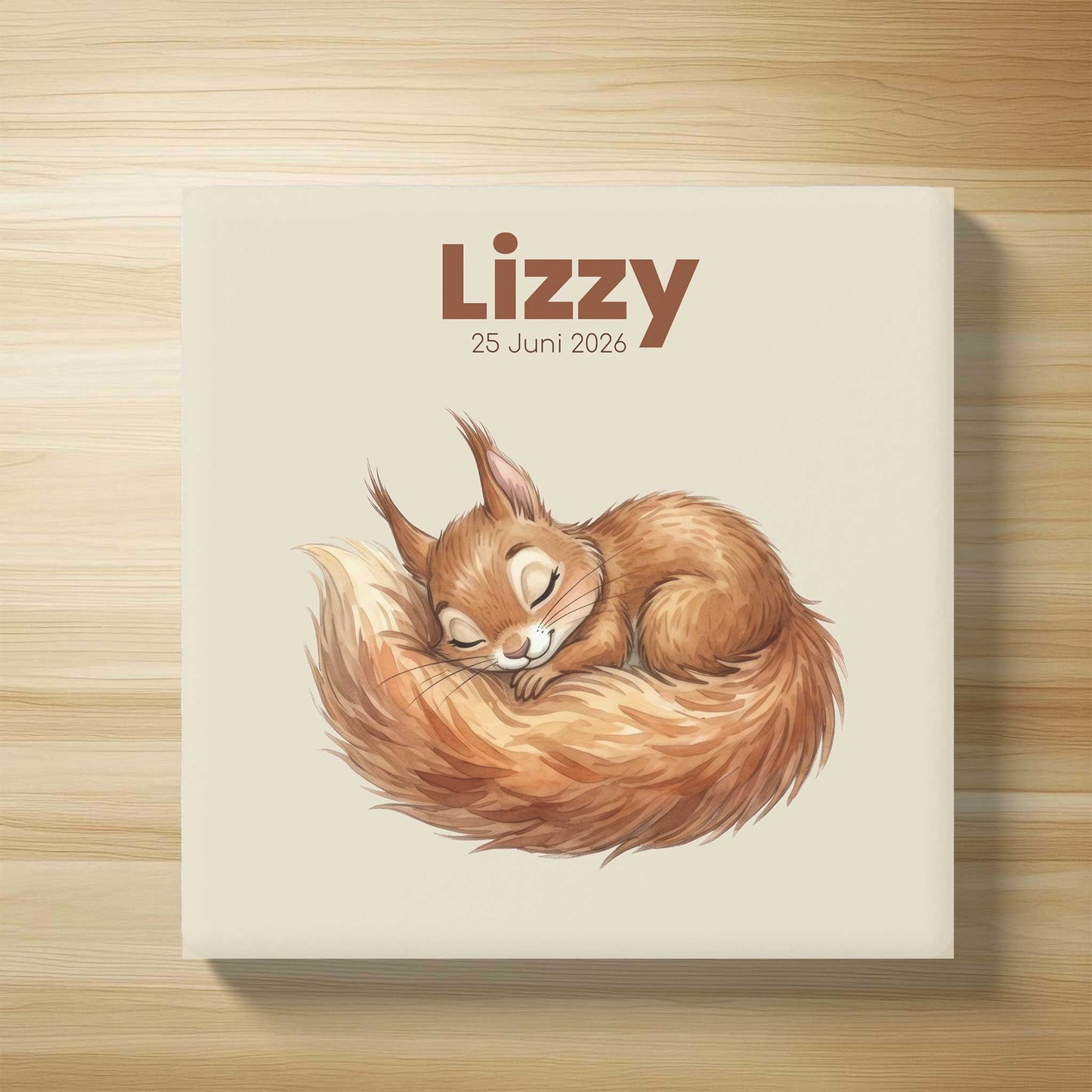 Gepersonaliseerd keramisch geboortetegeltje met slapend eekhoorntje, naam Lizzy en geboortedatum 25 juni 2026 op lichte houten achtergrond in flatlay stijl.