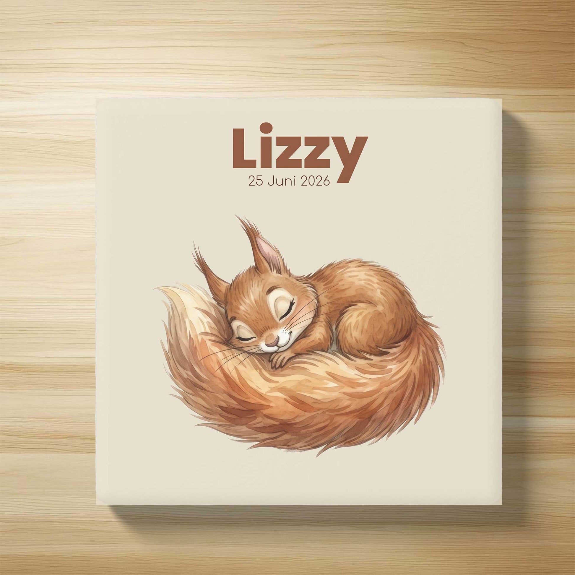 Gepersonaliseerd keramisch geboortetegeltje met slapend eekhoorntje, naam Lizzy en geboortedatum 25 juni 2026 op lichte houten achtergrond in flatlay stijl.
