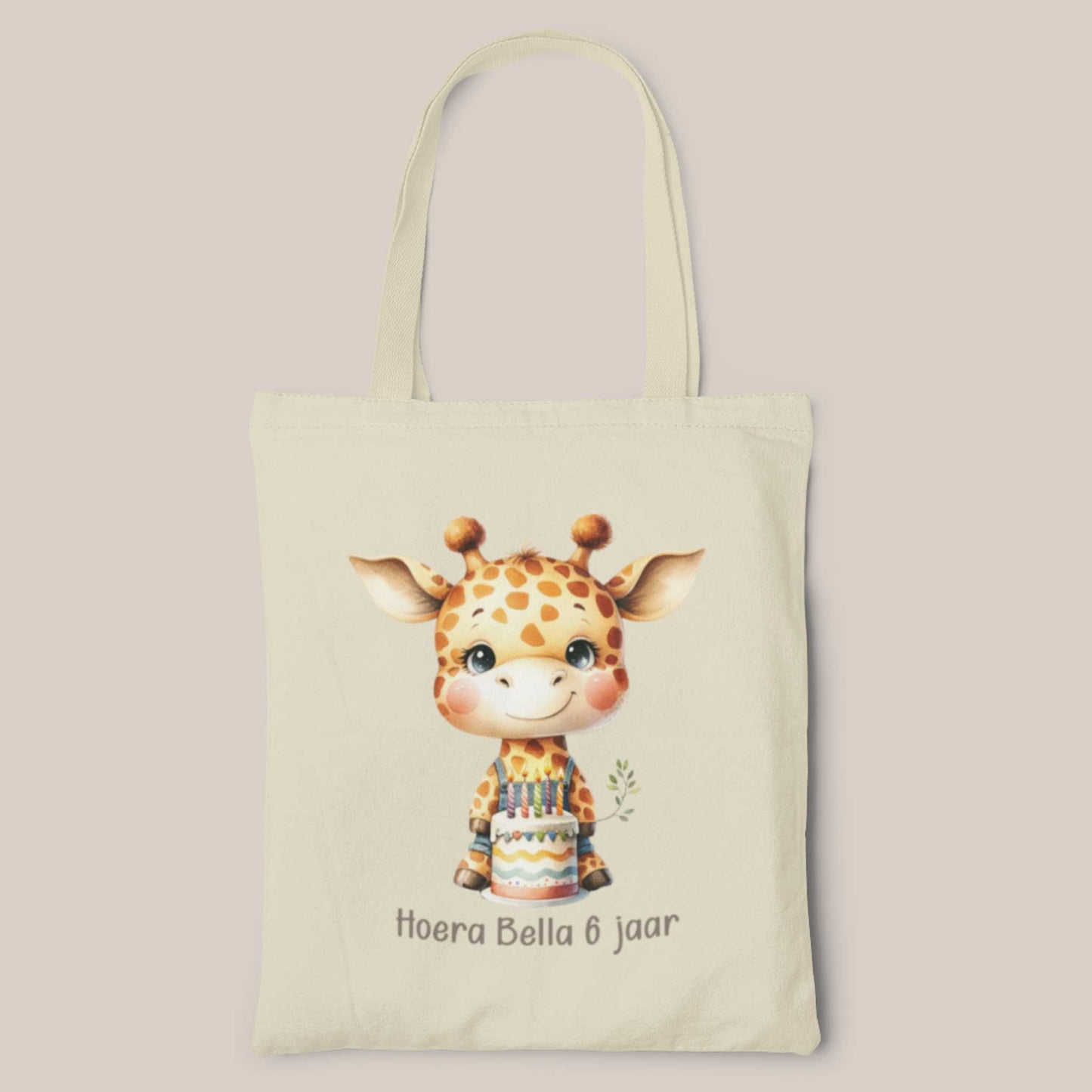 Gepersonaliseerde katoenen totebag met schattige giraf die een verjaardagstaart vasthoudt en de tekst 'Hoera Bella 6 jaar' op een lichte achtergrond.