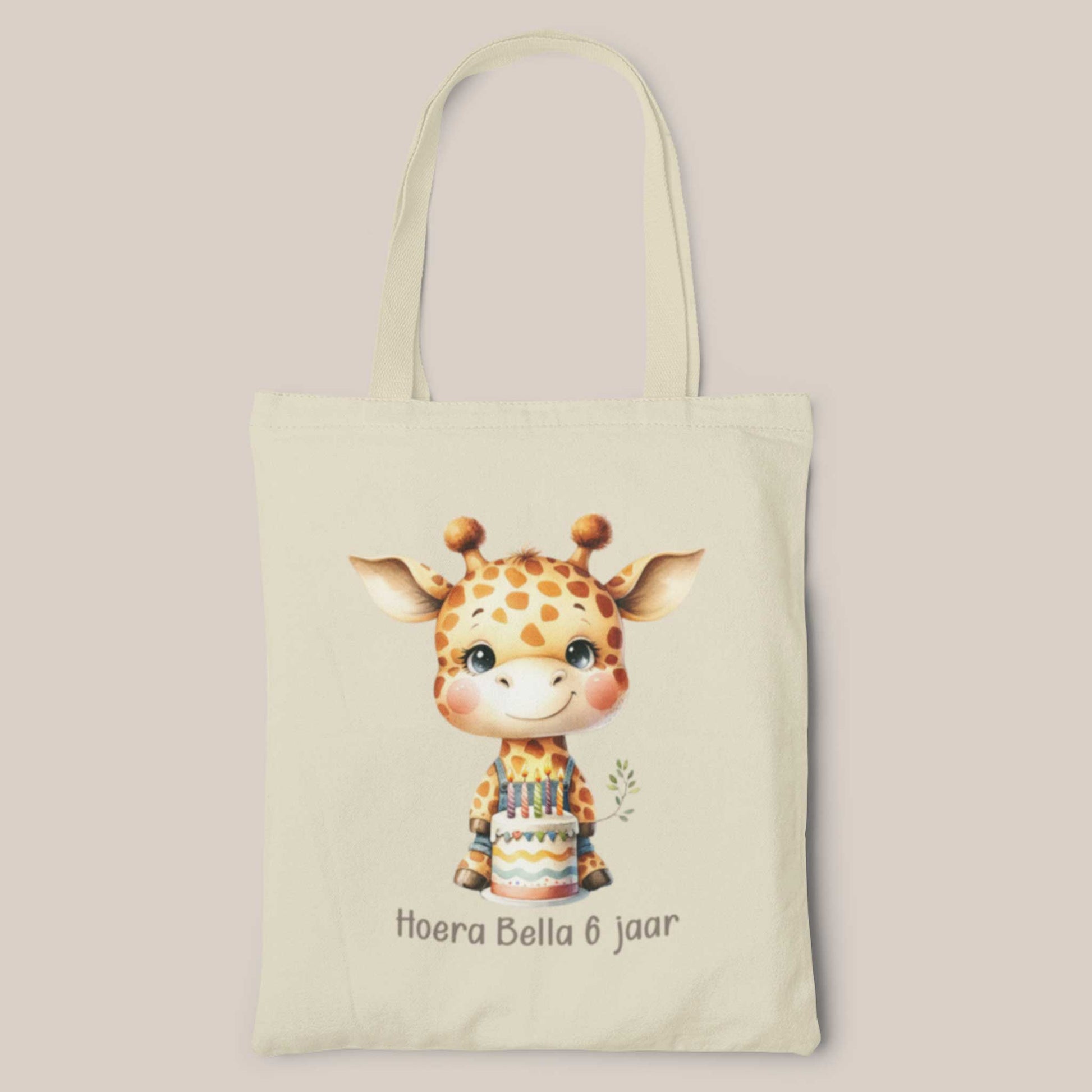 Gepersonaliseerde katoenen totebag met schattige giraf die een verjaardagstaart vasthoudt en de tekst 'Hoera Bella 6 jaar' op een lichte achtergrond.