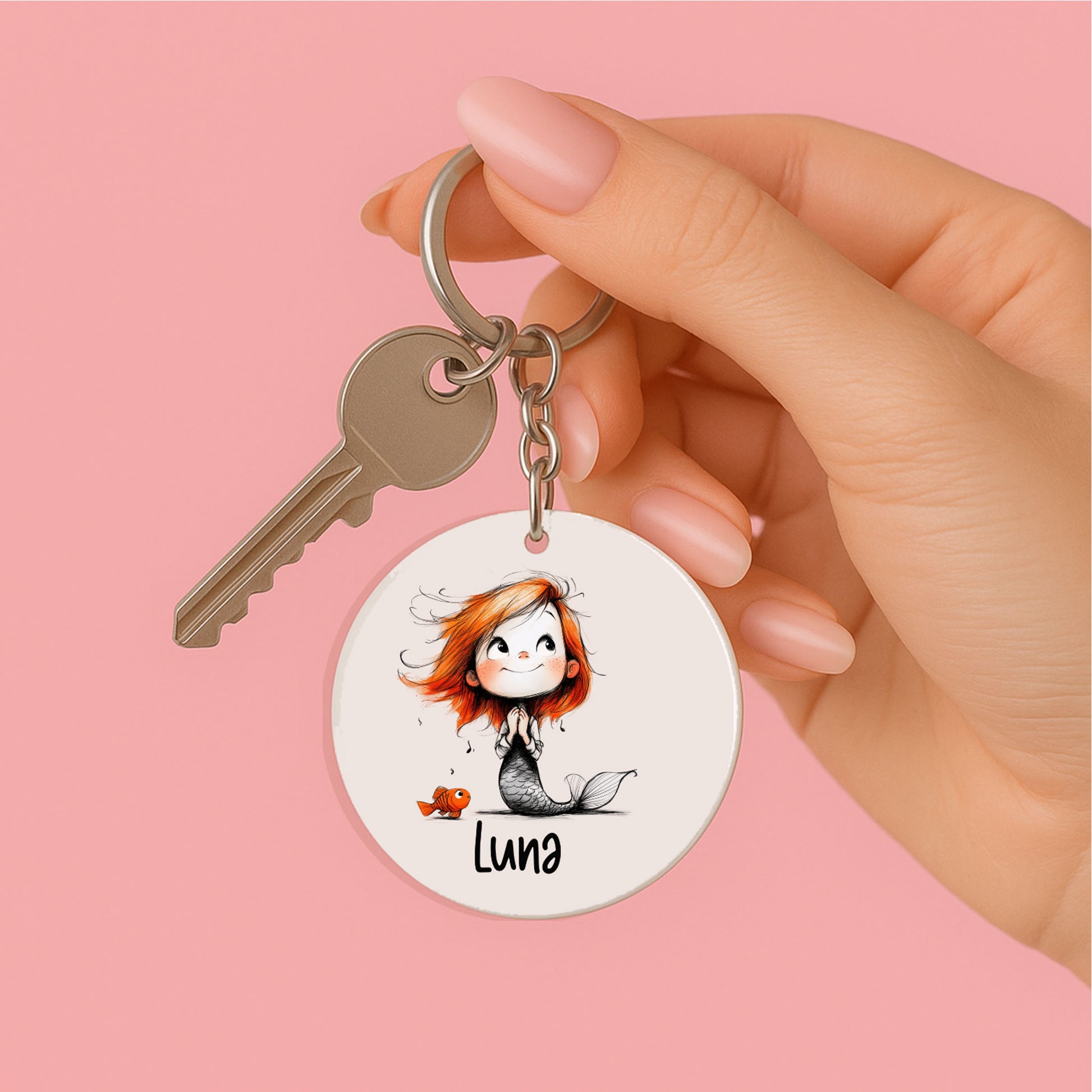 Hand houdt een gepersonaliseerde zeemeermin sleutelhanger met voorbeeldnaam Luna, metalen sleutelring en sleutel.