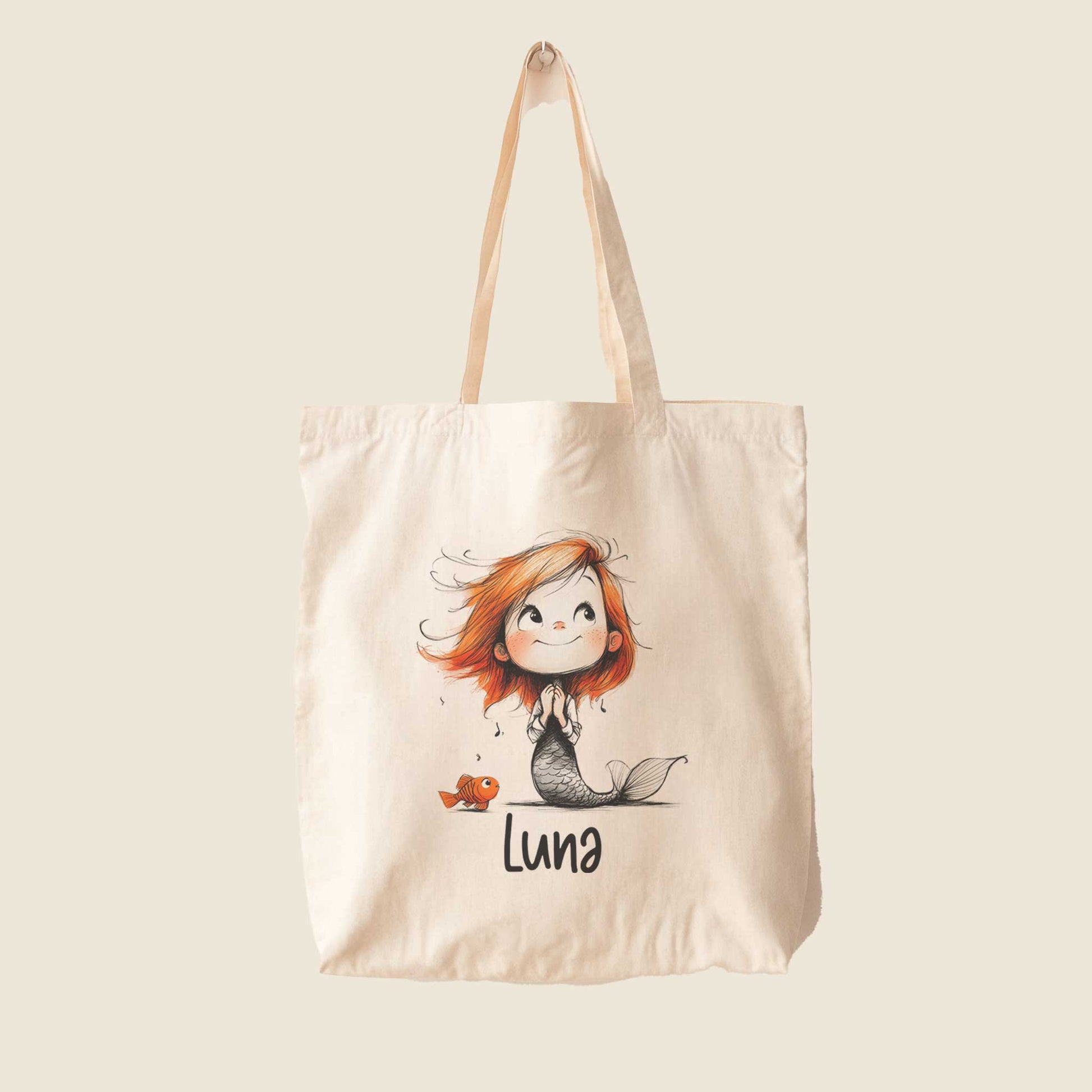 Vrijstaande naturelkleurige totebag bedrukt met een zeemeermin, een klein visje en een gepersonaliseerde naam.
