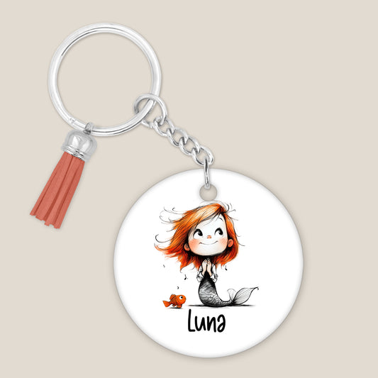 Ronde gepersonaliseerde sleutelhanger met zeemeermin, klein visje en voorbeeldnaam Luna op een lichte achtergrond.