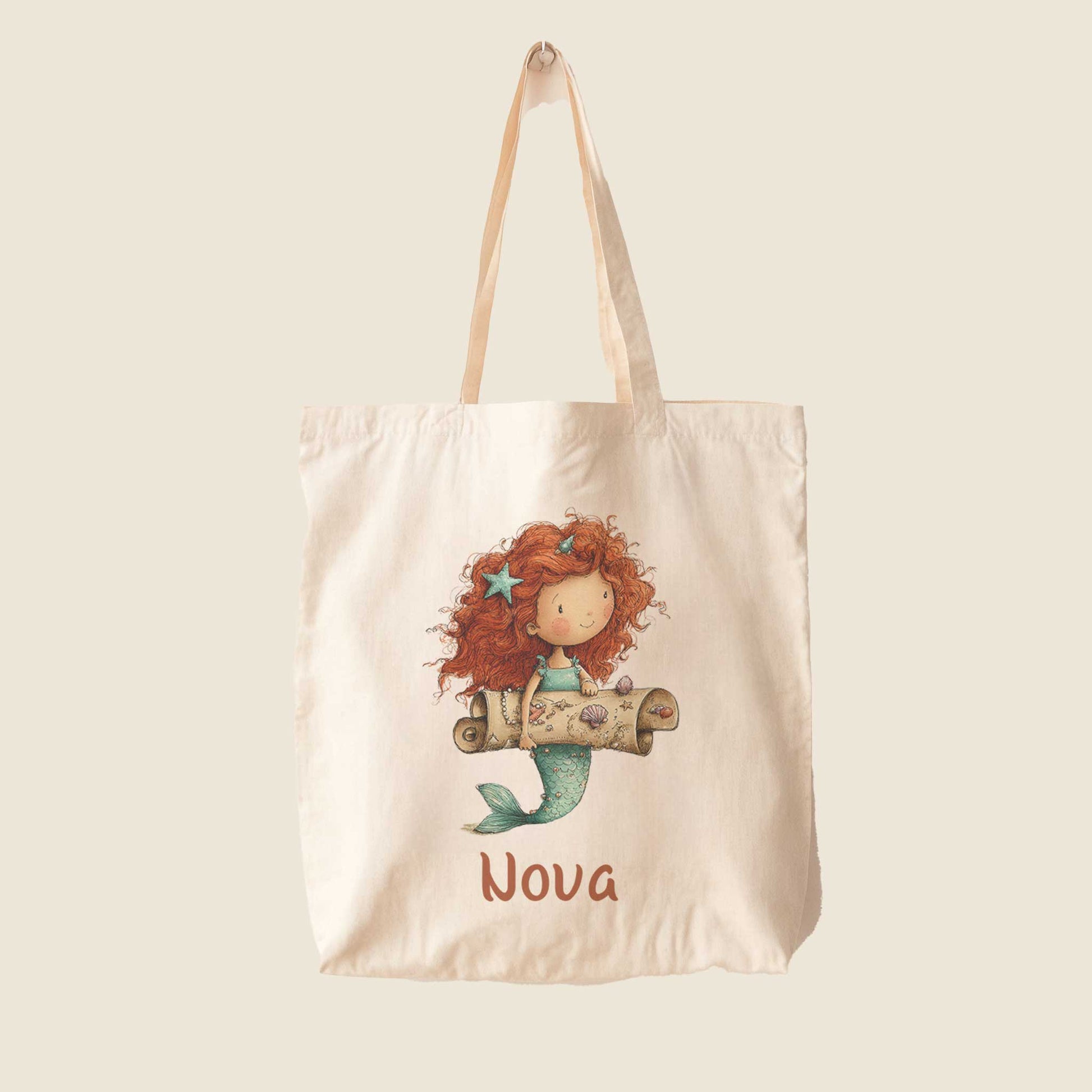 Vrijstaande katoenen totebag met naam Nova op lichte achtergrond met illustratie van een zeemeermin en schatkaart.