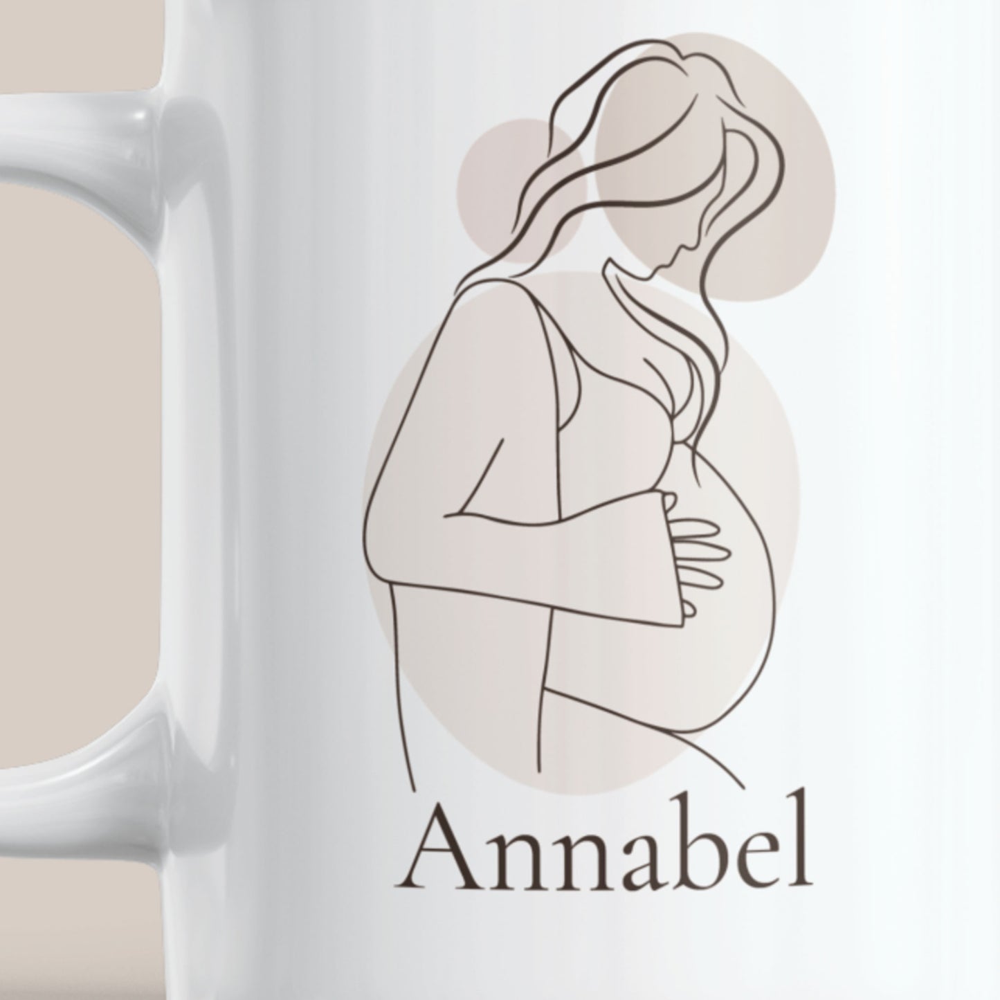 Witte keramische zwangerschapsmok met minimalistische lijntekening van een zwangere vrouw in neutrale beige tinten en de naam Annabel. Detailfoto van het gepersonaliseerde ontwerp op de mok.