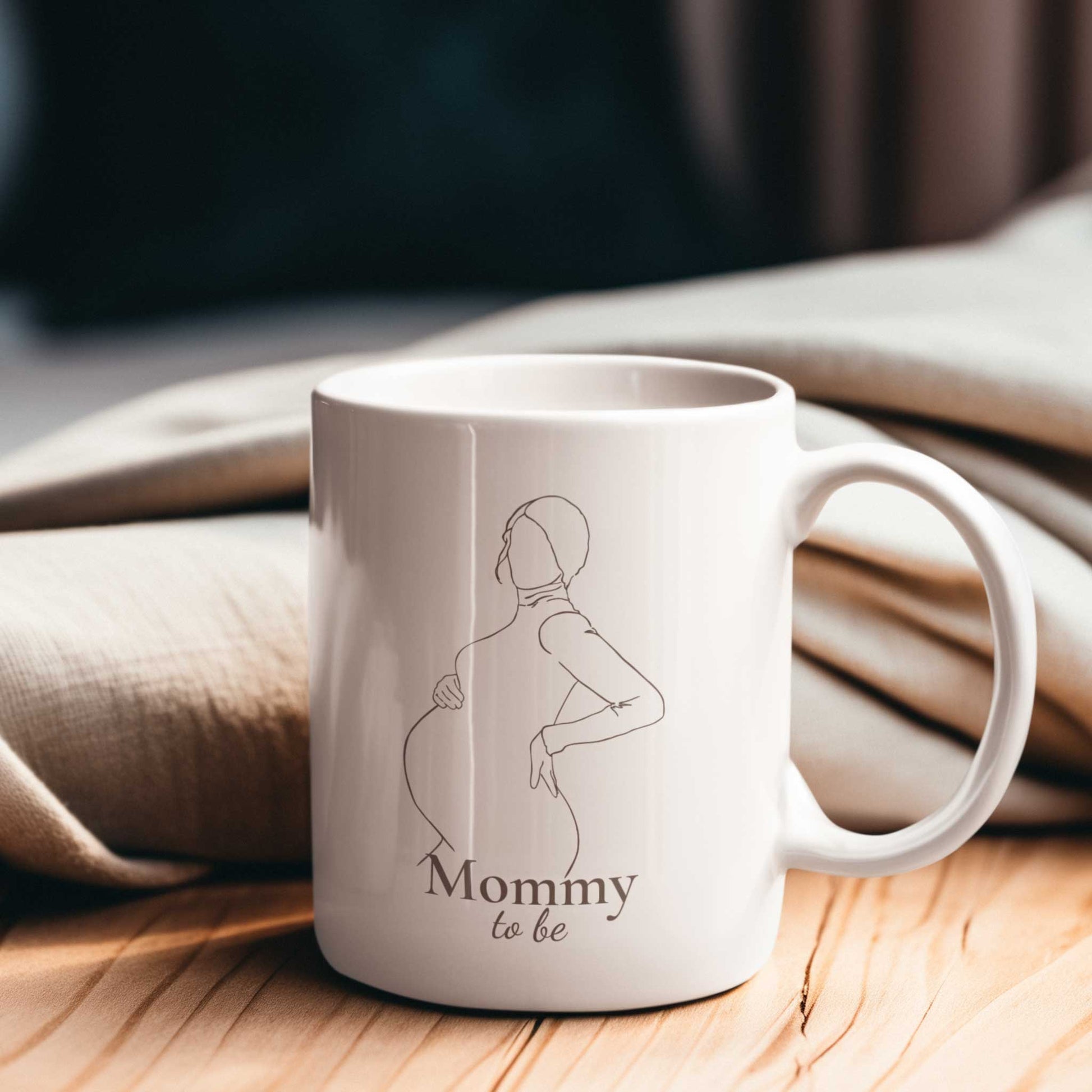 Witte Mommy to be mok met minimalistisch zwangerschapsontwerp op een houten tafel met warme zachte stoffen op de achtergrond