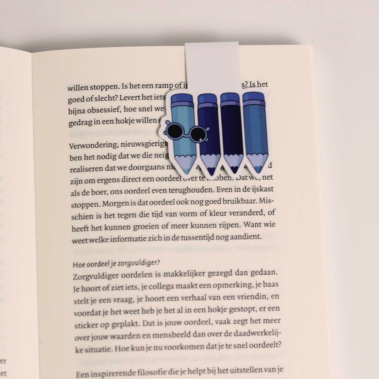 Magnetische boekenlegger met blauwe potloden vastgeklikt over een pagina van een open boek als bladwijzer