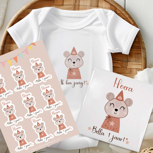Giftset verjaardag: rompertje, stickervel met 9 stickers en keramisch tegeltje met muis en tekst ‘Hoera Bella 1 jaar!’ bij elkaar gepresenteerd
