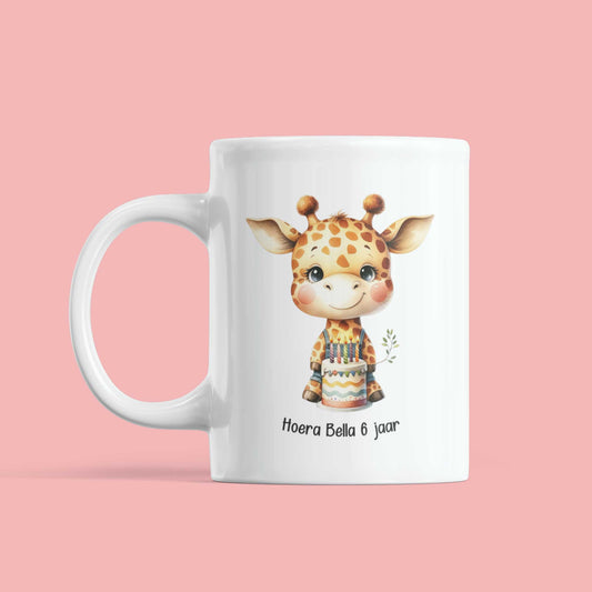 Witte mok met giraf en verjaardagstaart, tekst ‘Hoera Bella 6 jaar’, op roze achtergrond