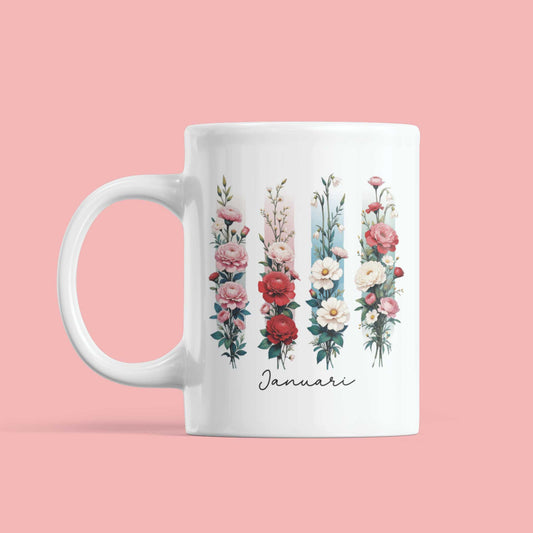Witte mok met anjers en sneeuwklokjes in aquarelstijl en ‘Januari’ in sierlijke brushletters, met zichtbare brushdetails.