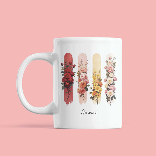 Witte mok tegen roze achtergrond met geboortebloemen van juni – roos en kamperfoelie – in warme aquarelstijl en brushaccenten.