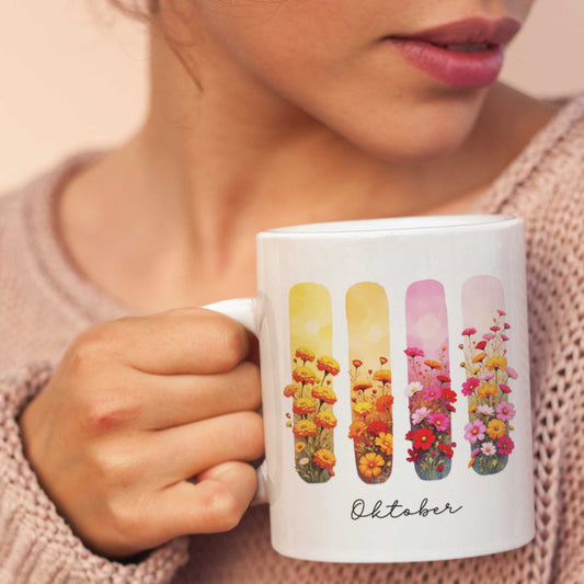 Vrouw in zachte trui houdt een mok vast met goudsbloem en cosmosbloem in warme tinten en brushachtergrond, tekst ‘Oktober’ zichtbaar