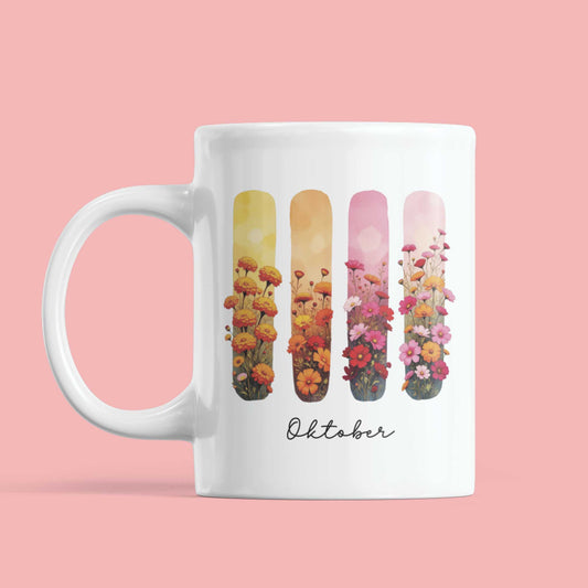 Witte mok tegen roze achtergrond met oranje en roze bloemen, geboortebloemen van oktober op aquarelstroken – elegant en herfstachtig.