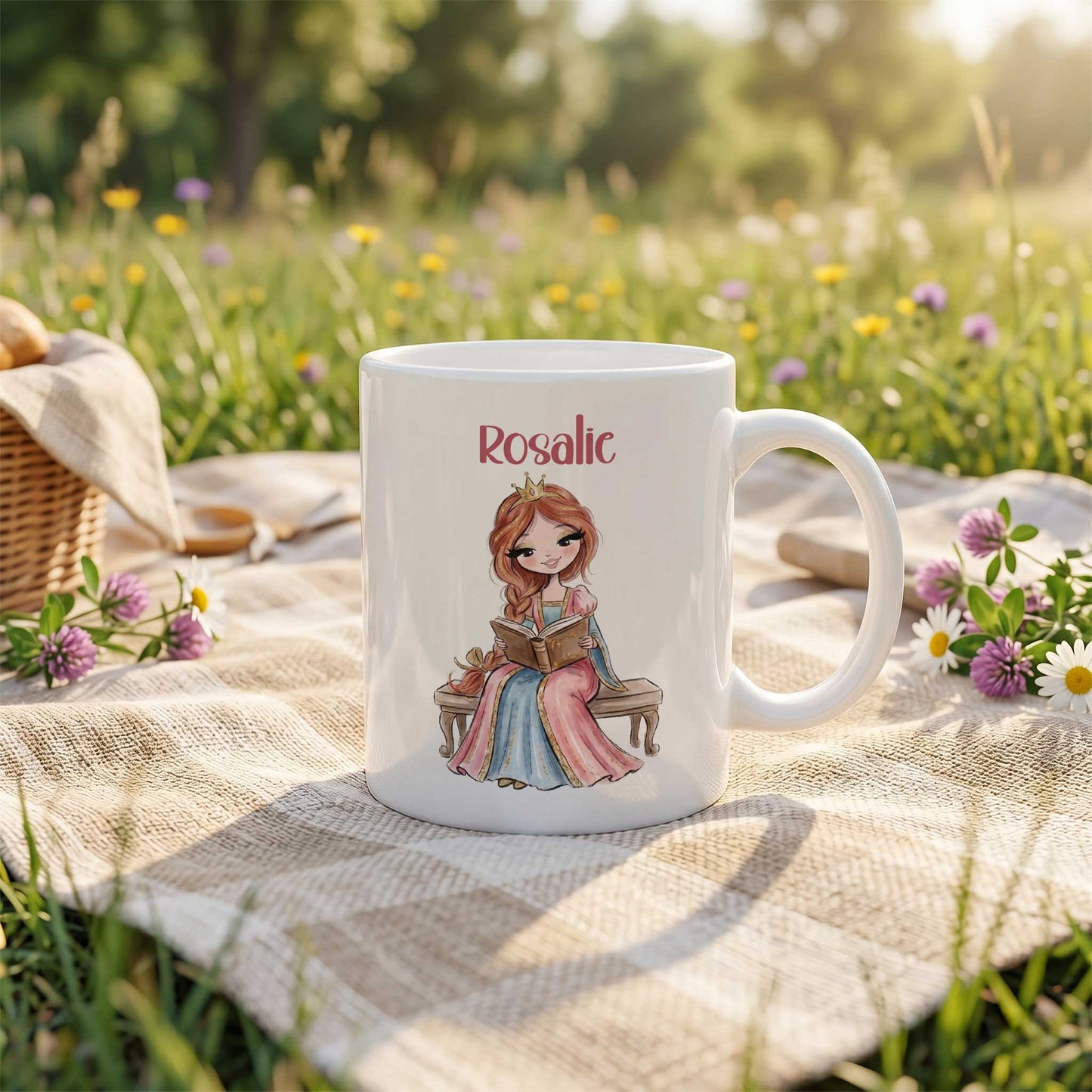Witte mok met een prinses die op een bankje een boek leest, geplaatst op een picknickkleed in een bloemenweide. Boven de illustratie staat de naam Rosalie.