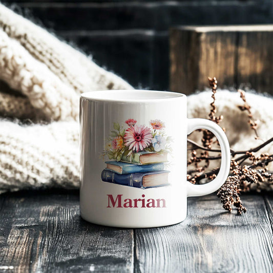 Gepersonaliseerde boekenmok op houten tafel met cozy sfeer, bedrukt met boeken, bloemen en naam "Marian"