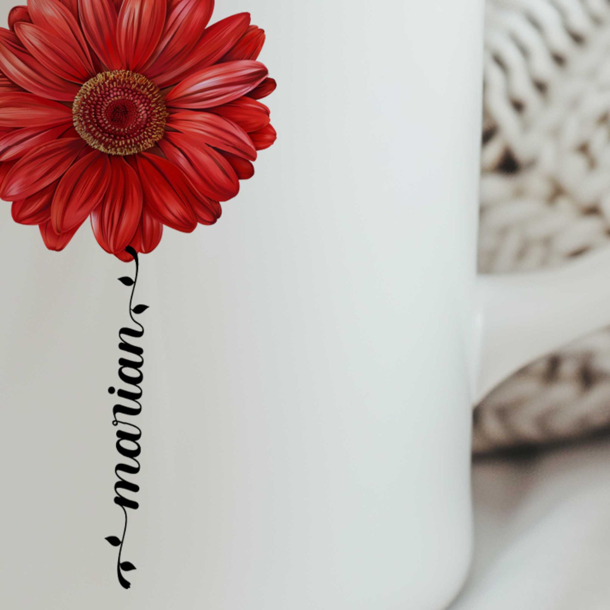 Close-up van een witte keramische mok met een rode gerbera en gepersonaliseerde naam als bloemsteel onder de bloem