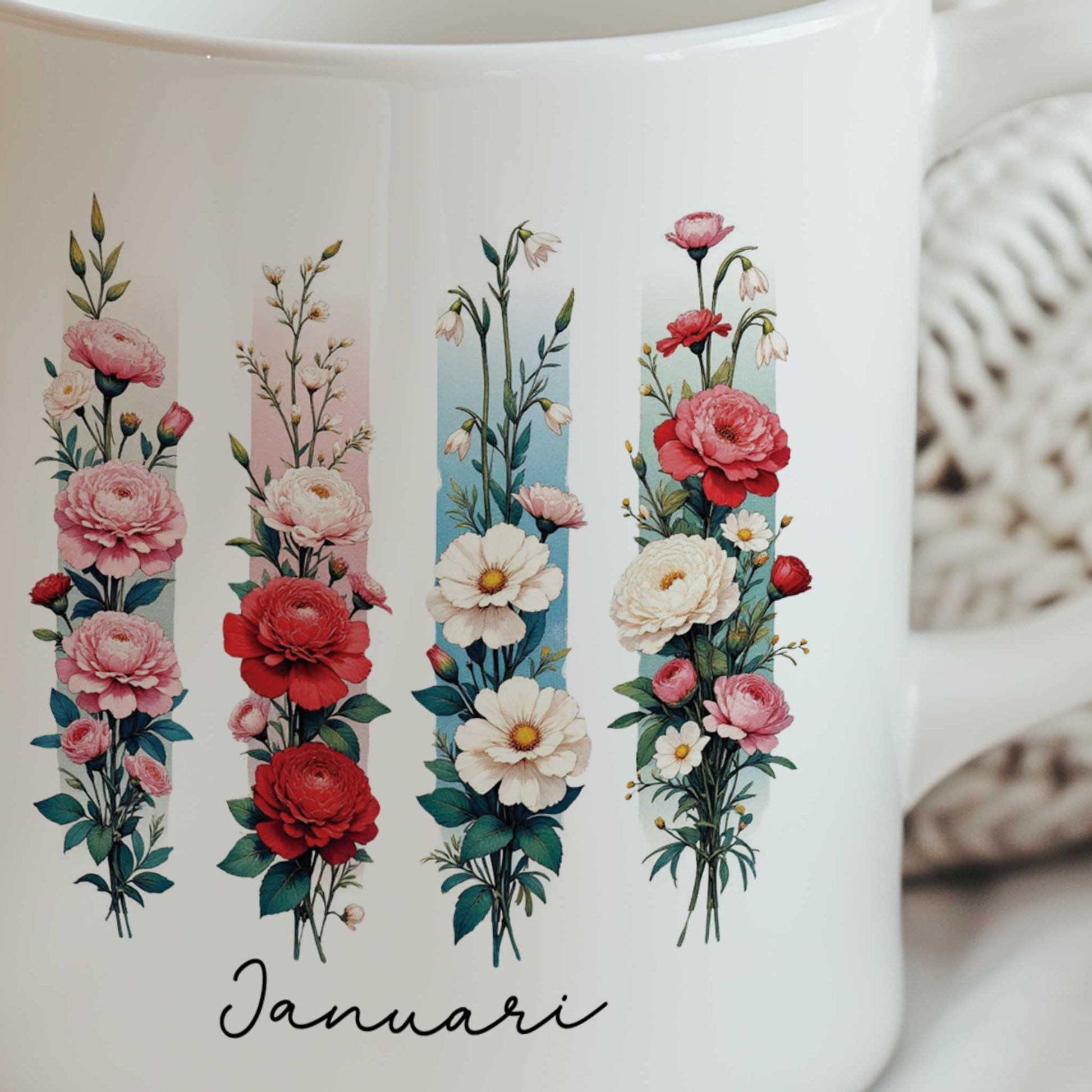 Close-up van de witte mok met de geboortebloem van januari in brush effect, waarop de bloemenillustratie en de tekst 'Januari' duidelijk zichtbaar zijn.