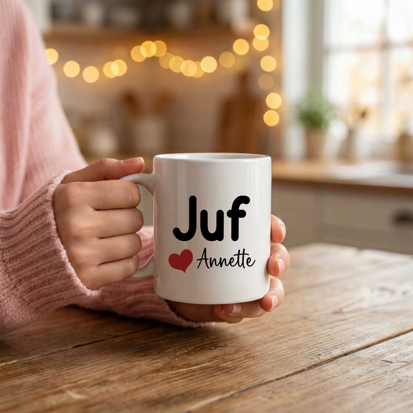 Sfeerfoto van een witte mok met de tekst Juf, een rood hartje en de naam Annette, vastgehouden in twee handen