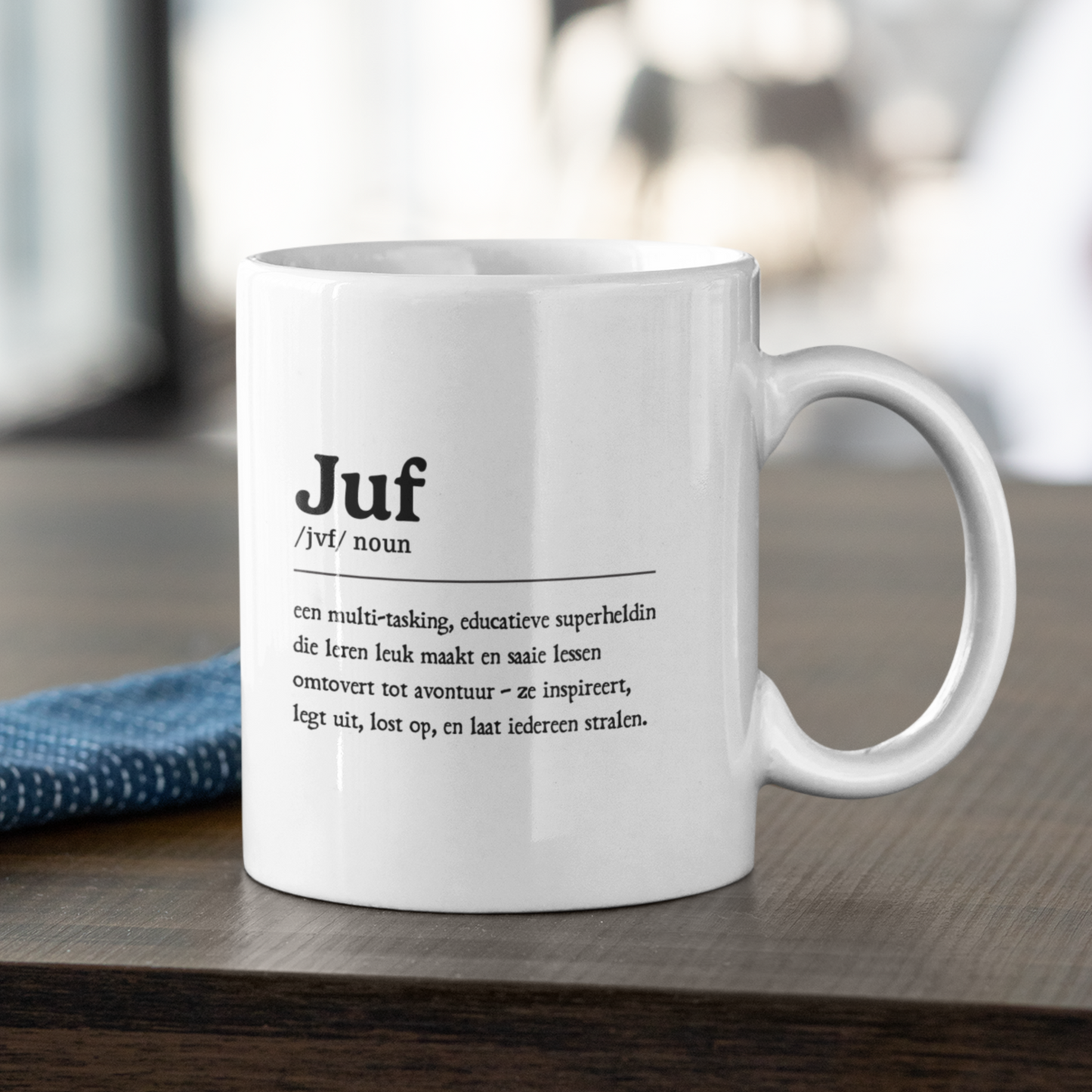 witte mok met een speelse definitie van ‘juf’ in de vorm van een ‘noun’ op een donker houten tafel