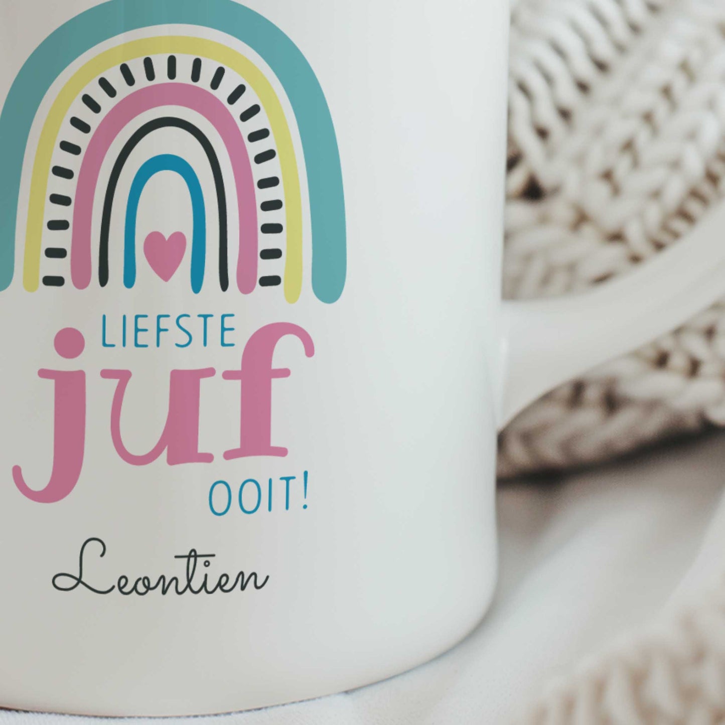 Close-up van witte juffenmok met pastel regenboog, tekst 'Liefste juf ooit!' en gepersonaliseerde naam onder het ontwerp