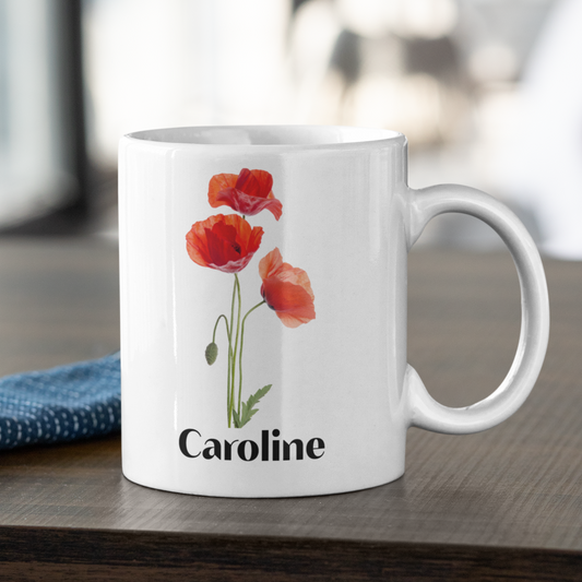 Witte mok met klaprozen en naam Caroline op houten tafel met blauw servet