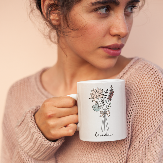 Vrouw houdt witte mok vast met lijntekening bloemen en de naam Linda, keramisch ontwerp