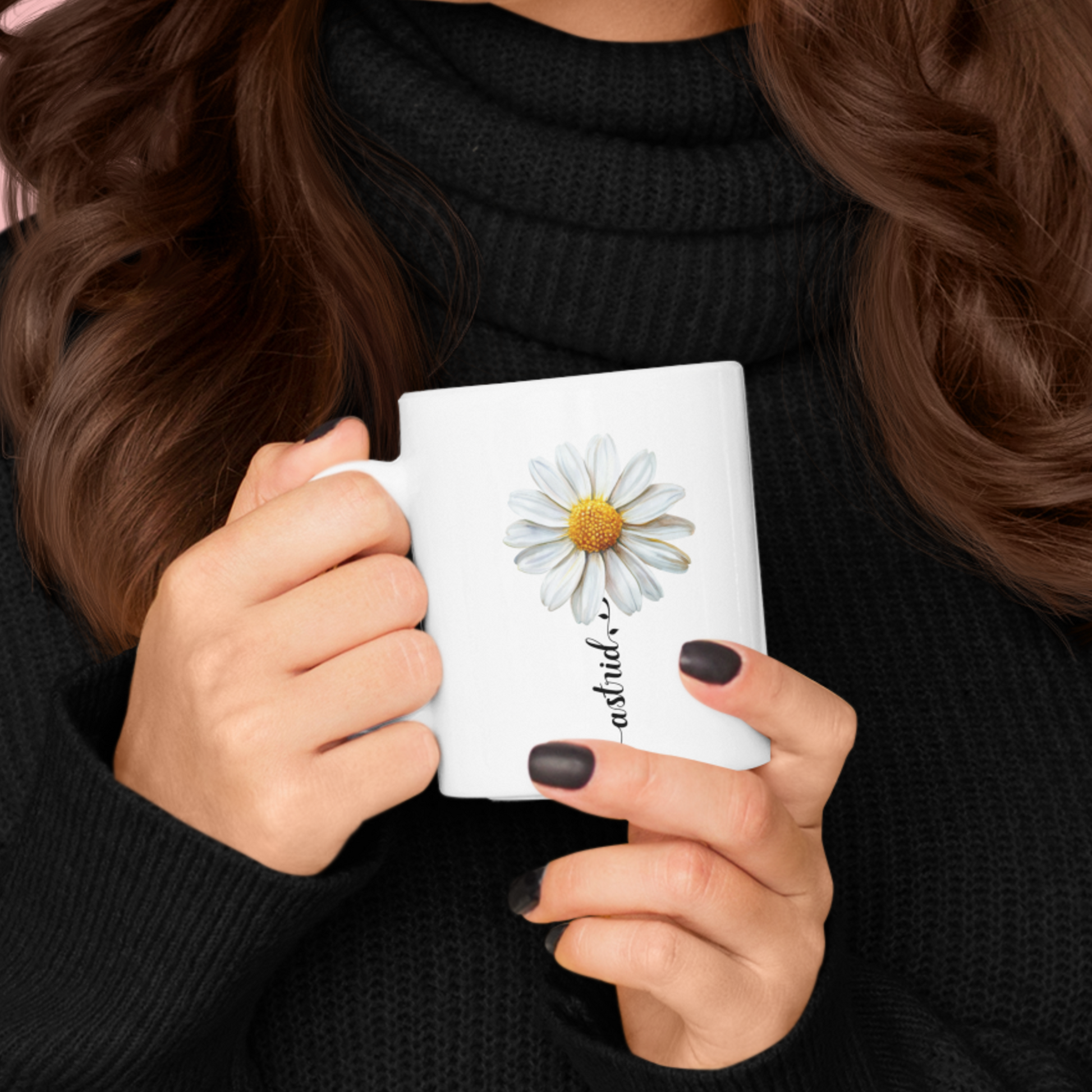 vrouw met zwarte coltrui die een mok vasthoudt, witte mok met madeliefje en personaliseerbare naam in sierlijke letters in een bloemstengel vorm in het zwart