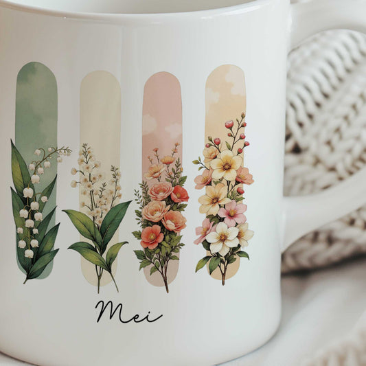 Close-up van een witte mok met een illustratie van de geboortebloemen van mei en de tekst Mei.