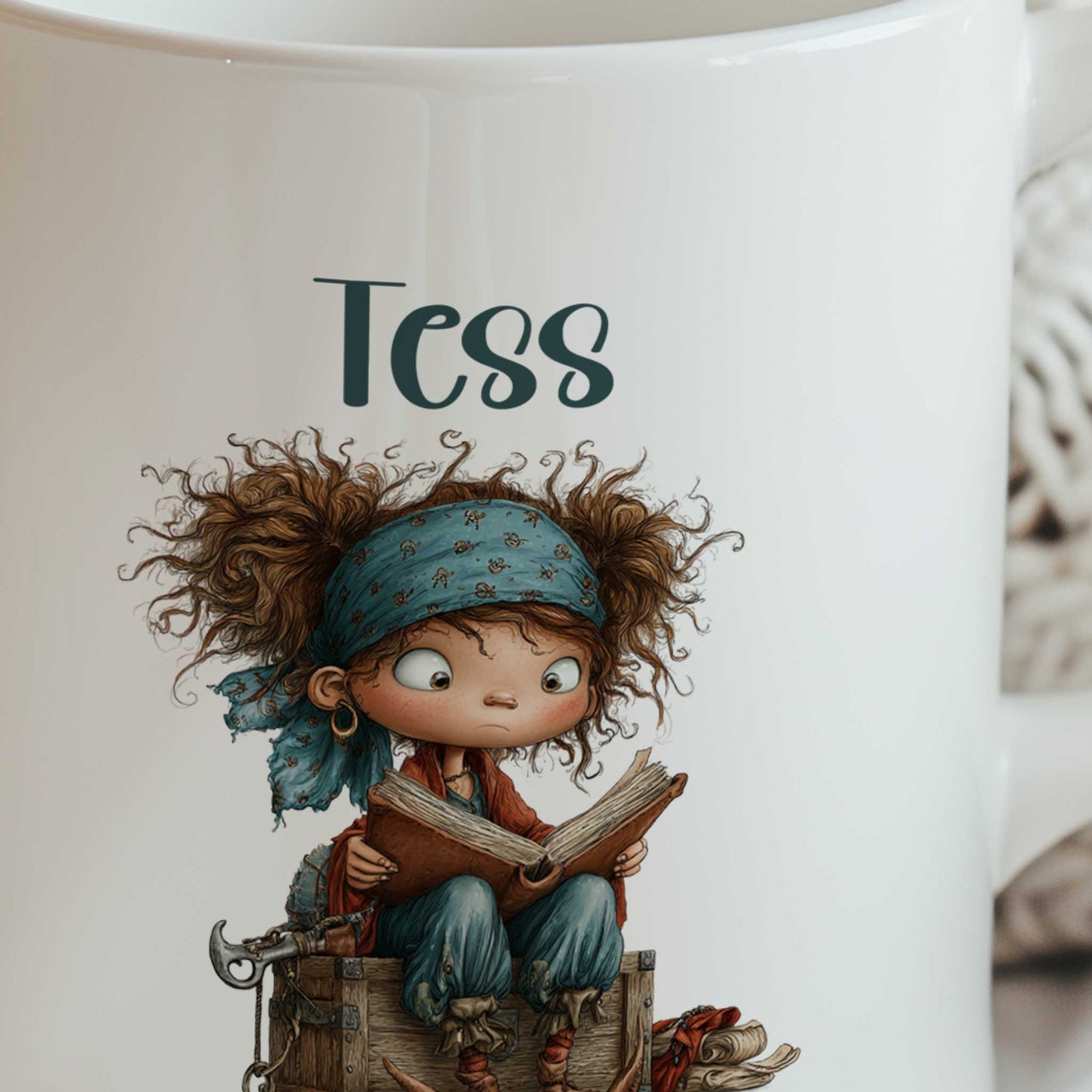 Close-up van een witte mok met de naam Tess boven een illustratie van een klein piratenkind dat op een houten kist zit en een boek leest.