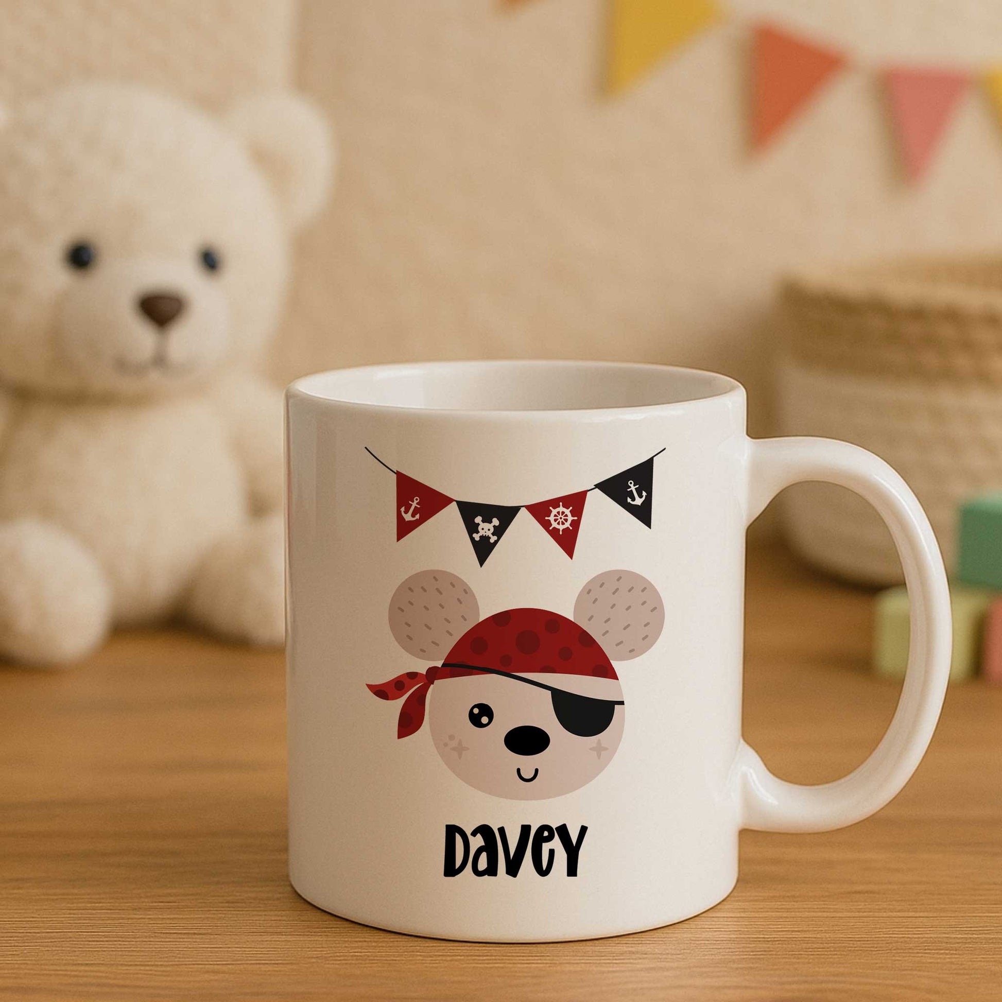 Witte mok met de naam Davey en een illustratie van een piratenbeer met ooglapje, rode bandana, schatkist en feestelijke vlaggetjes op een houten tafel in een kinderkamer.