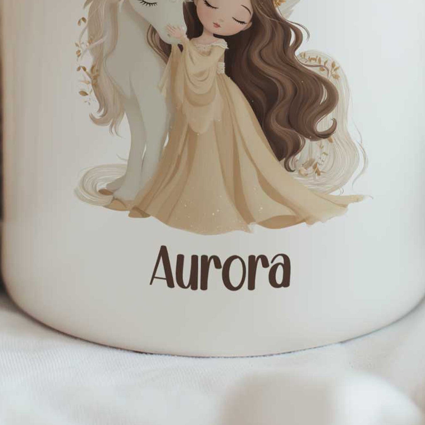 Close-up van een witte mok met een prinses die tegen een witte eenhoorn aanleunt. Onder de illustratie staat de naam Aurora.