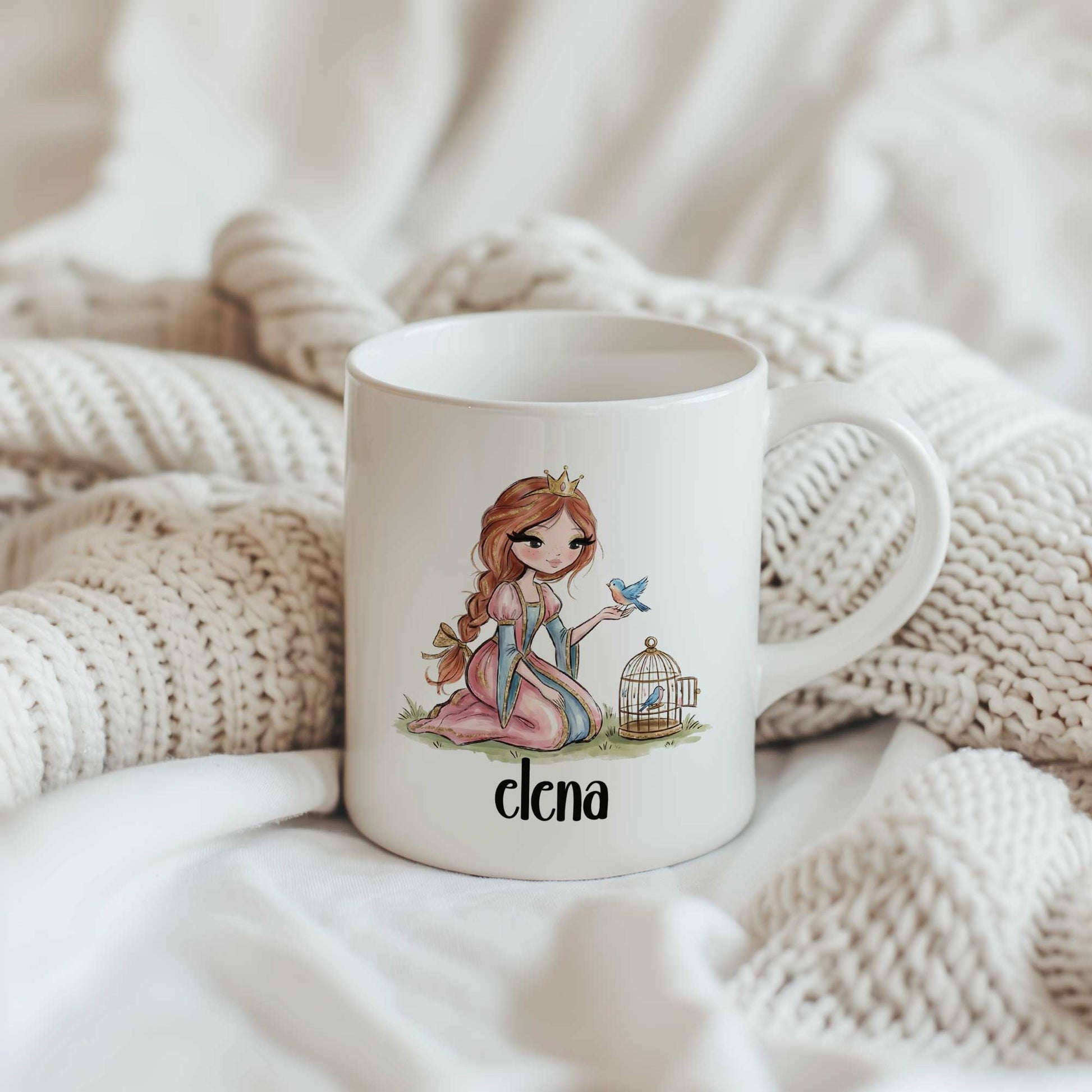 Witte mok met een prinses, een blauw vogeltje en de naam Elena tussen zachte beige dekens.