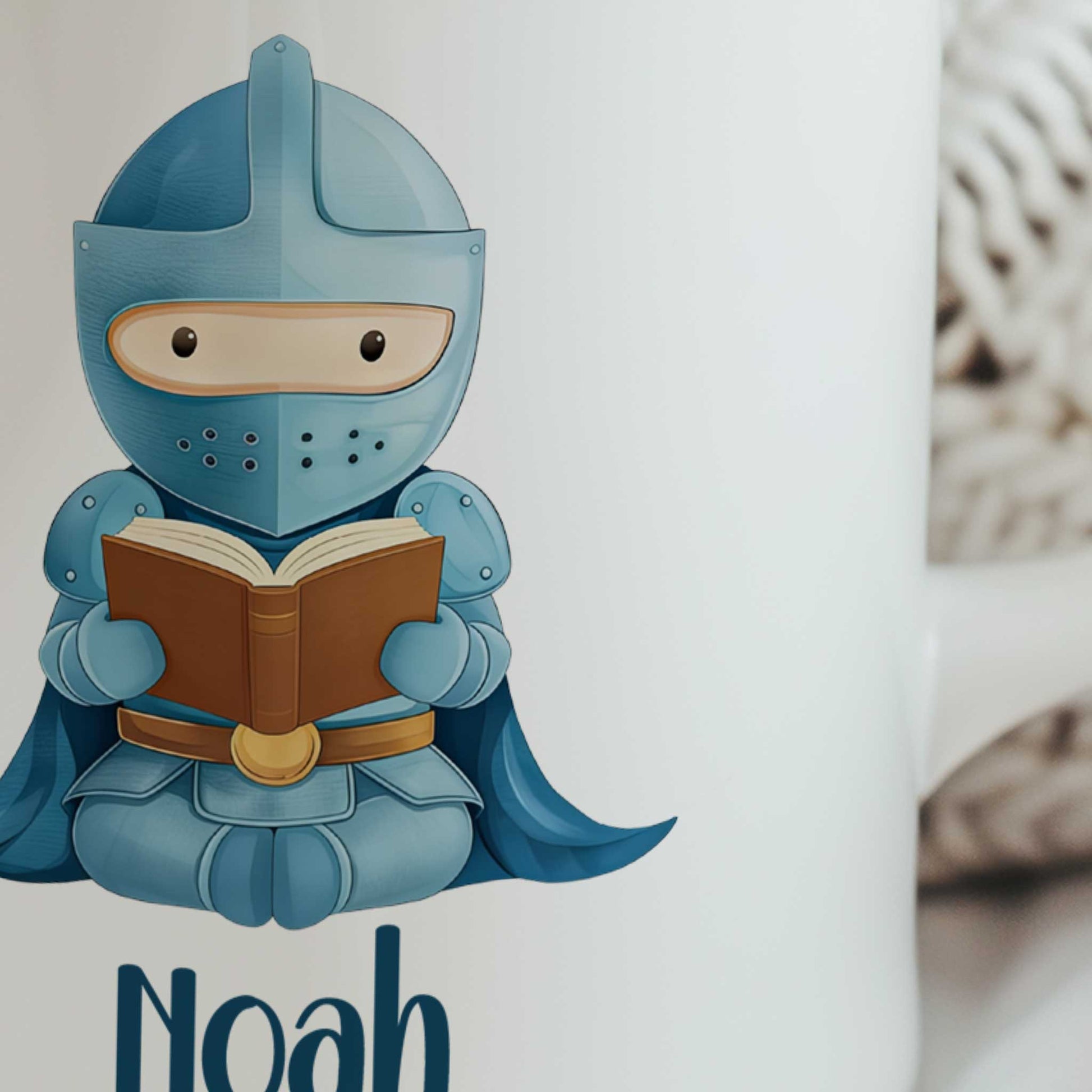 Close-up van een witte mok met een blauwe ridder die een boek leest en de naam Noah.
