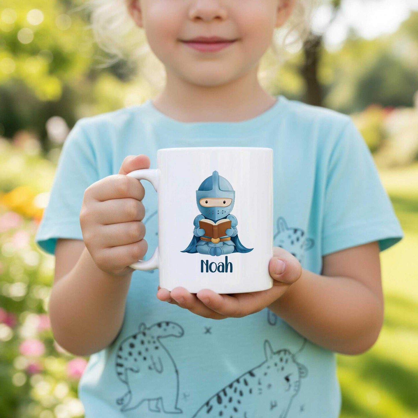 Sfeerfoto van een kind dat een witte mok met een blauwe ridder die een boek leest en de naam Noah vasthoudt.