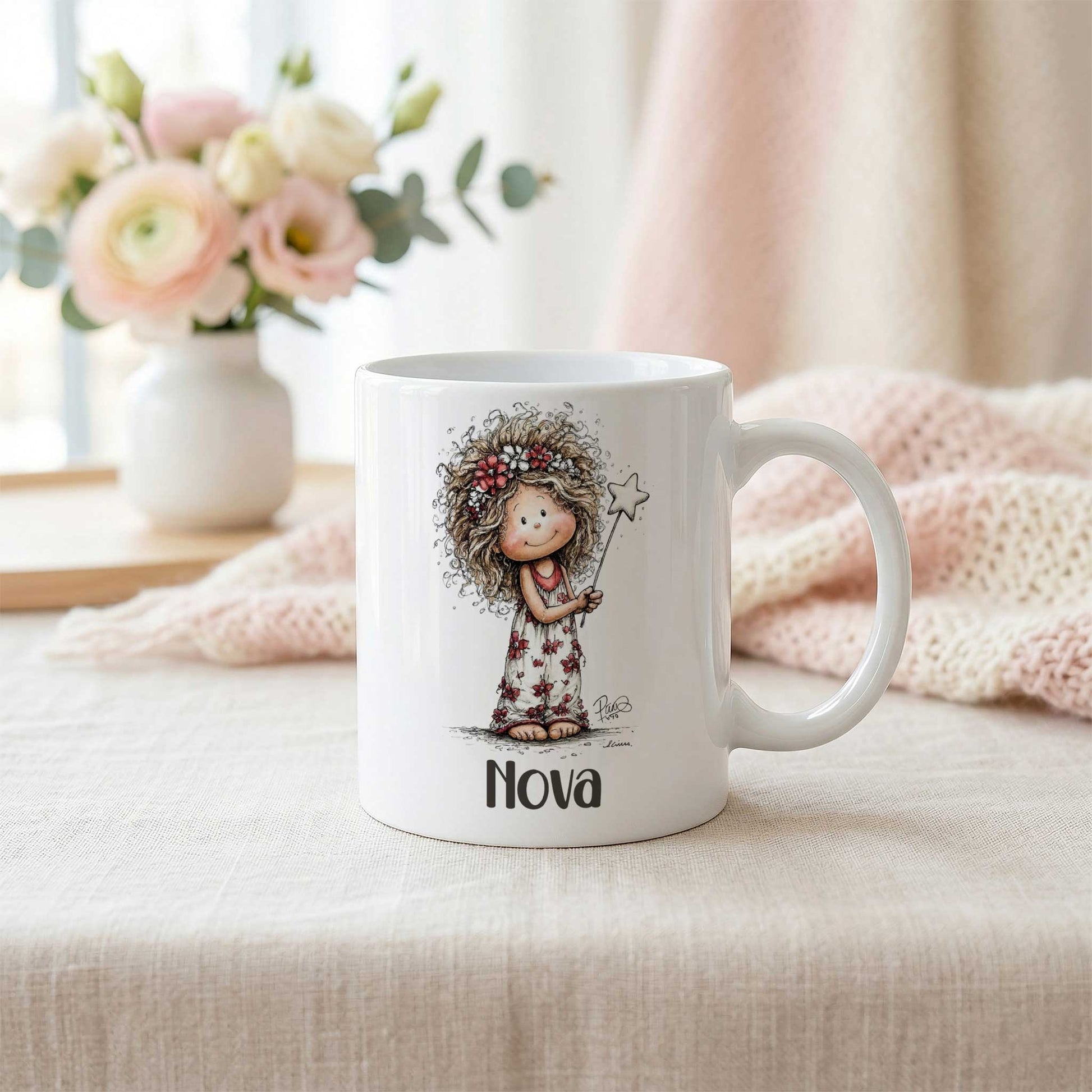 Witte mok met fee-illustratie en naam Nova op een lichte tafel naast een zachtroze gebreide deken en een vaas met bloemen.