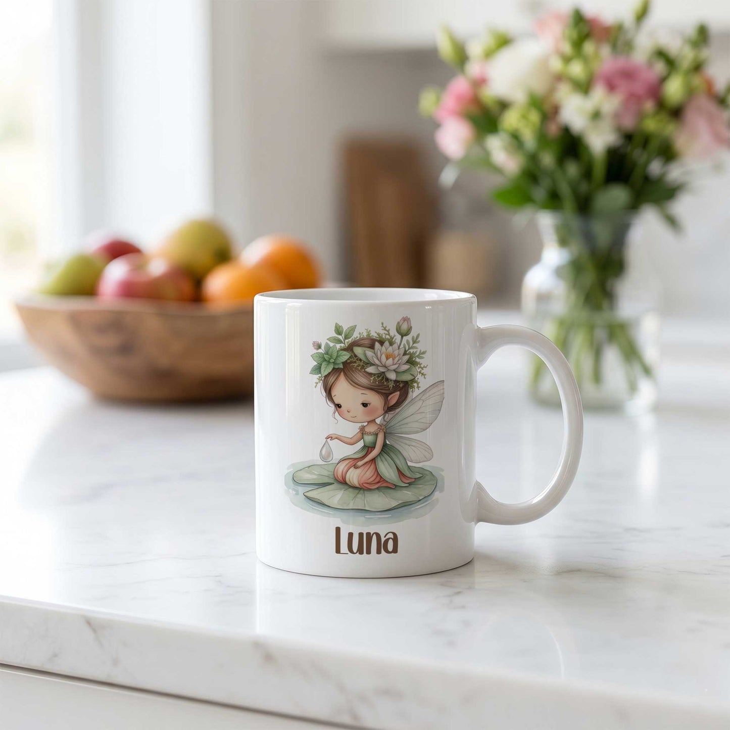 Witte mok met waterleliefee en naam Luna op een licht keukenblad met een schaal fruit en een bloemenvaas op de achtergrond.