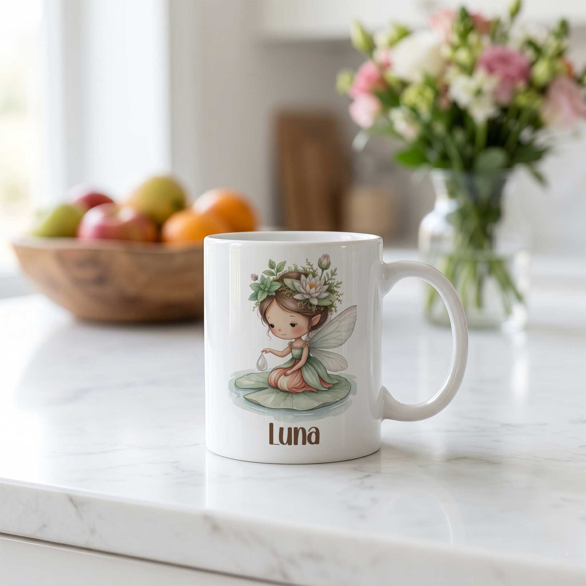 Witte mok met waterleliefee en naam Luna op een licht keukenblad met een schaal fruit en een bloemenvaas op de achtergrond.