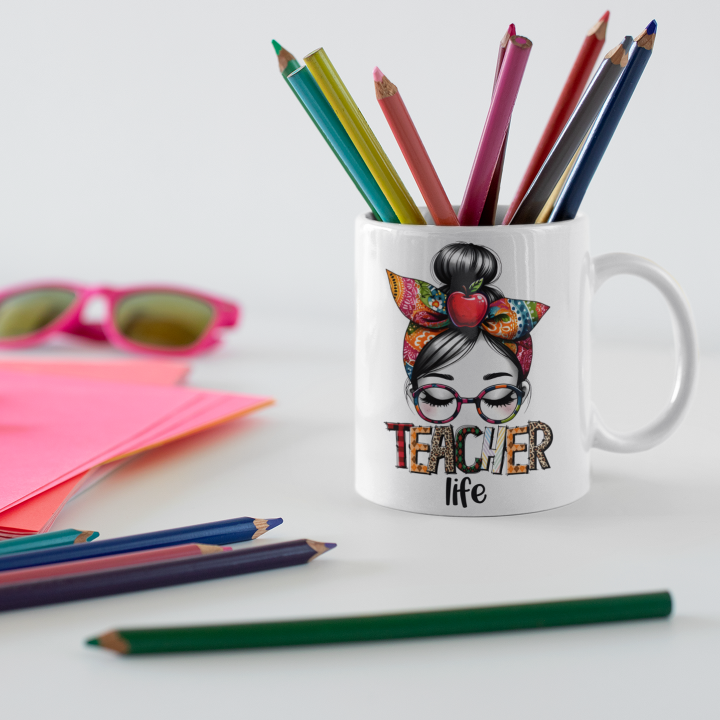 mok met teacher life op bureau met kleurpotloden en roze papier