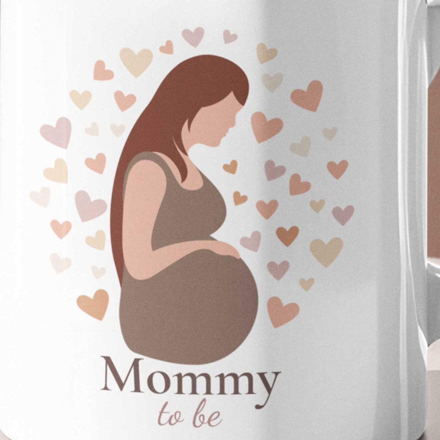 Close-up van een witte Mommy To Be mok met illustratie van een zwangere vrouw en zachte hartjes in neutrale beige en roze tinten.