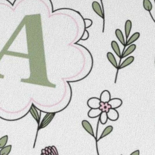 close up van Muismat met antislip onderkant, met patroon van lijn bloemen in licht groene en roze kleuren en in het midden een Monogram van de letter van iemands naam die aanpasbaar is