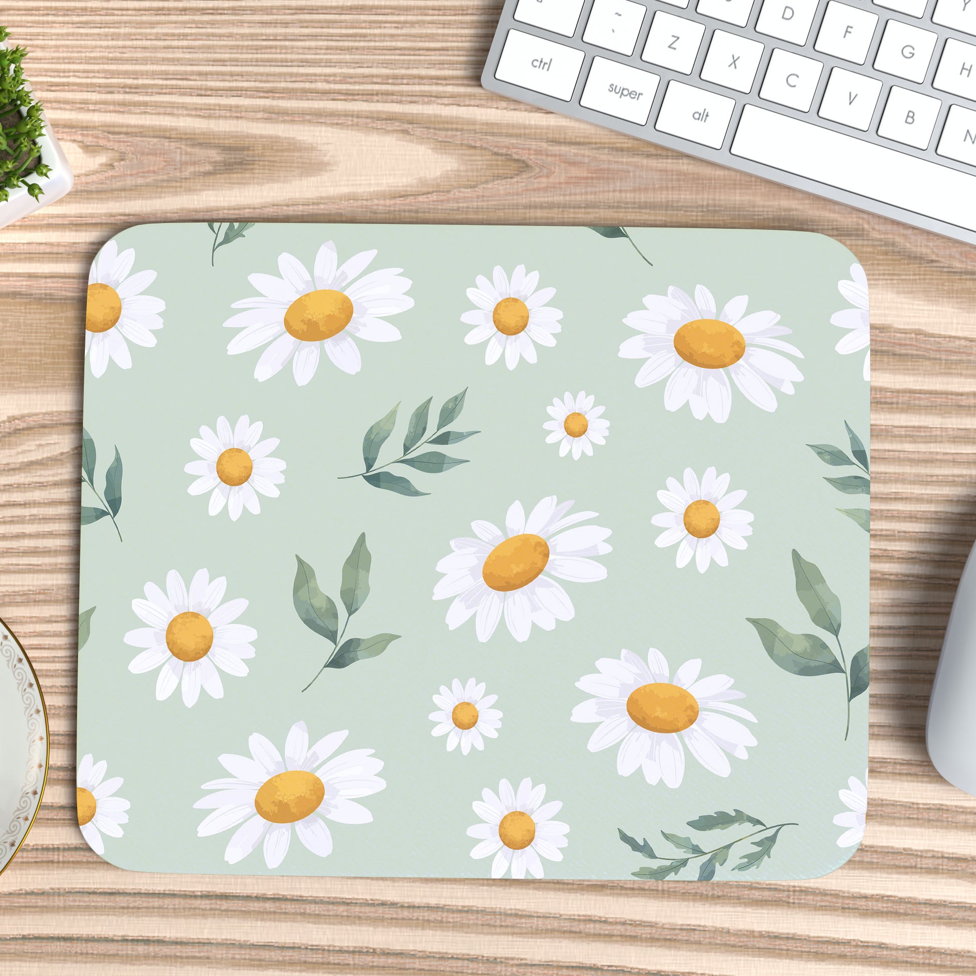muismat met een bloemenpatroon, Margrietjes en blaadjes op een licht groene ondergrond op een grenen bureau blad met een wit toetsenbord